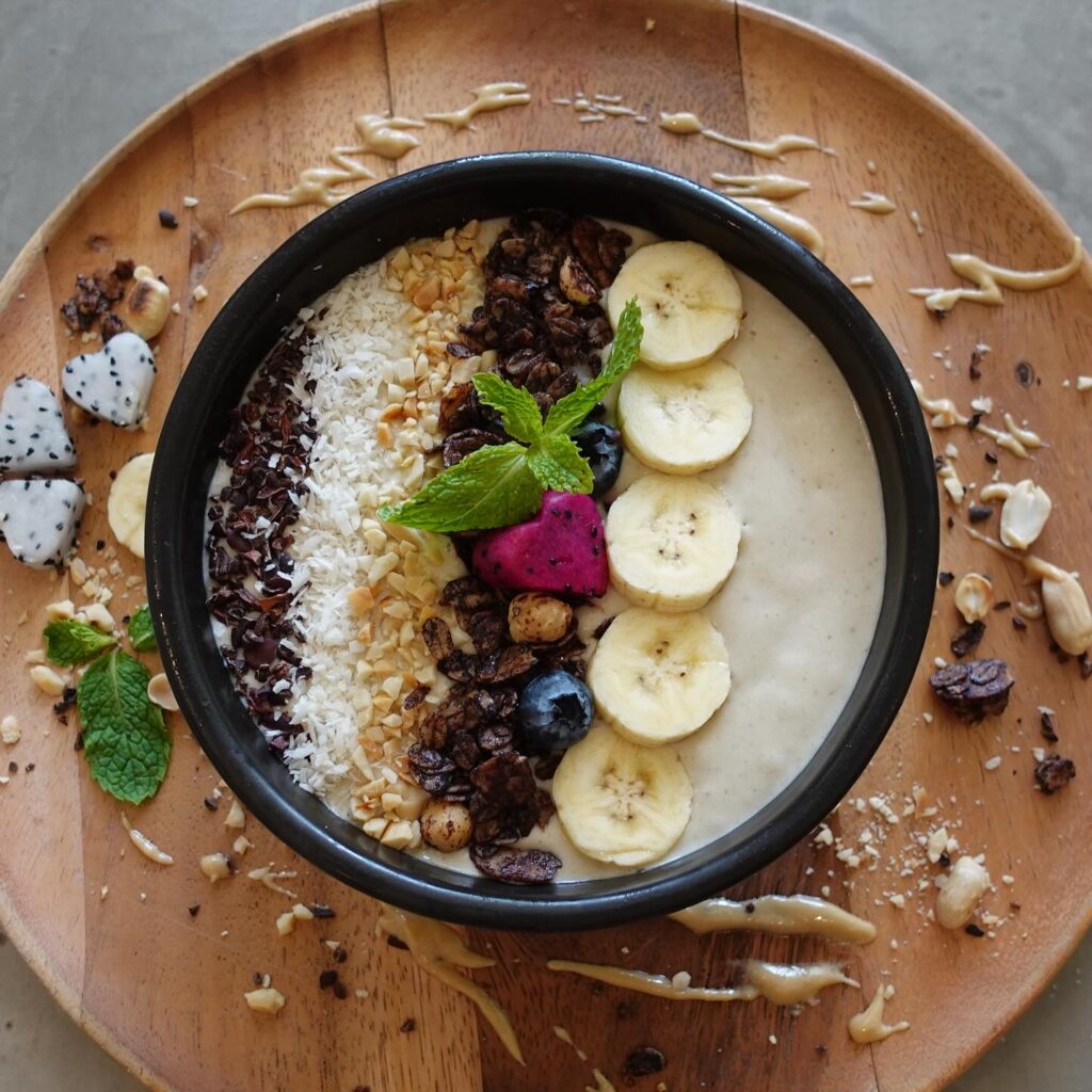 colorful vegan smoothie bowl with sliced banana, berries, coconut, and nuts at kiaora cafe Koh Phayam