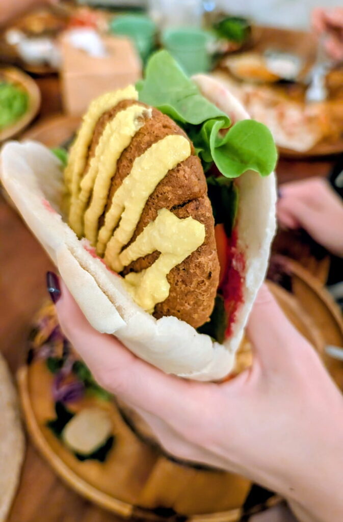 falafel patty with yellow cream sauce in a pita sandwich at pure vegan heaven in Koh Phangan