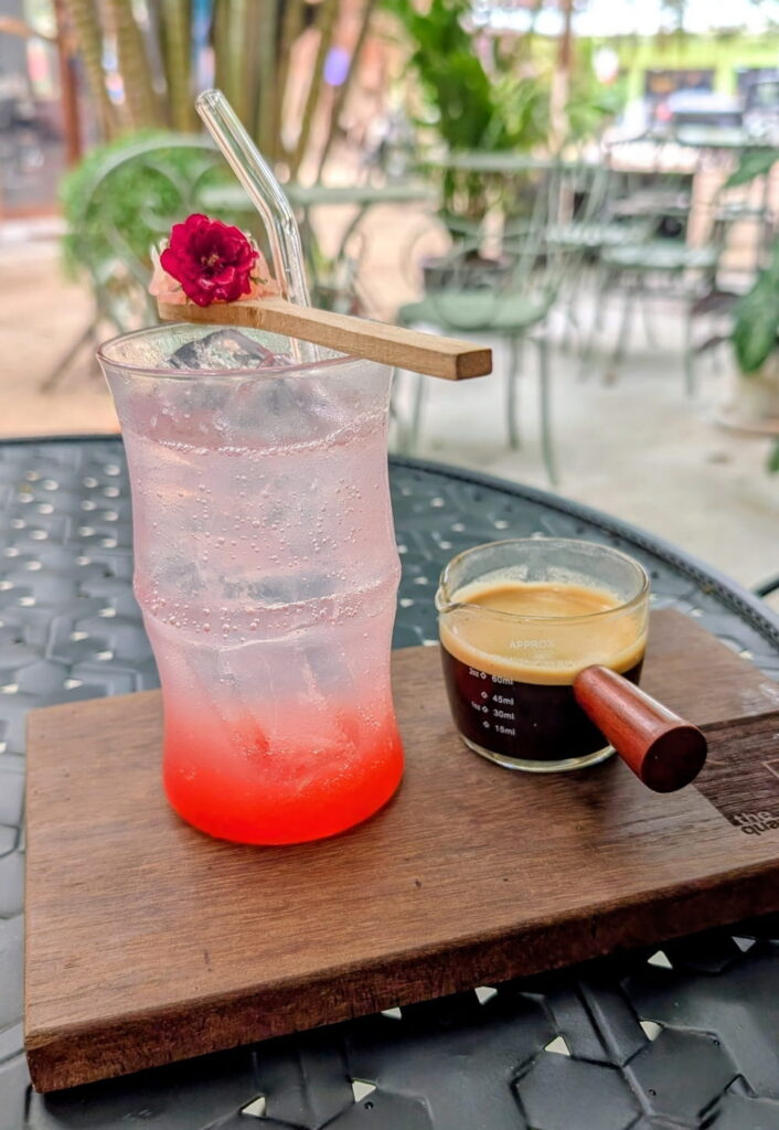 a tall glass with tonic water and pink berry syrup next to a short of espresso at the quarter in Koh Phangan