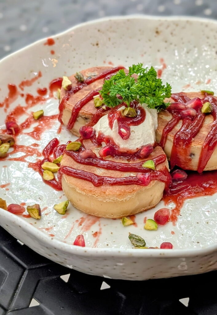 a stack of three mini golden pancakes topped with raspberry syrup at the quarter in Koh Phangan