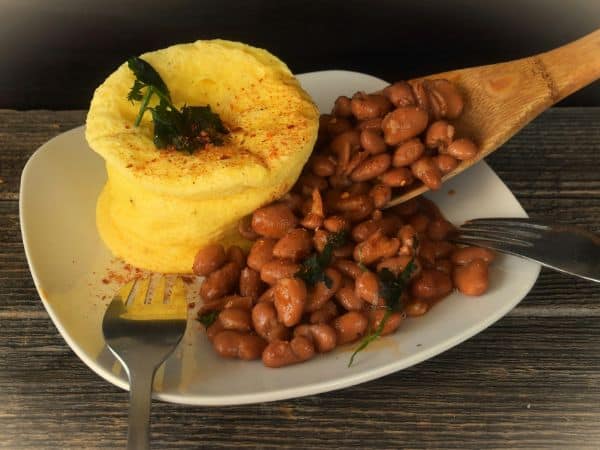 a bowl of pinto beans with yellow tortillas