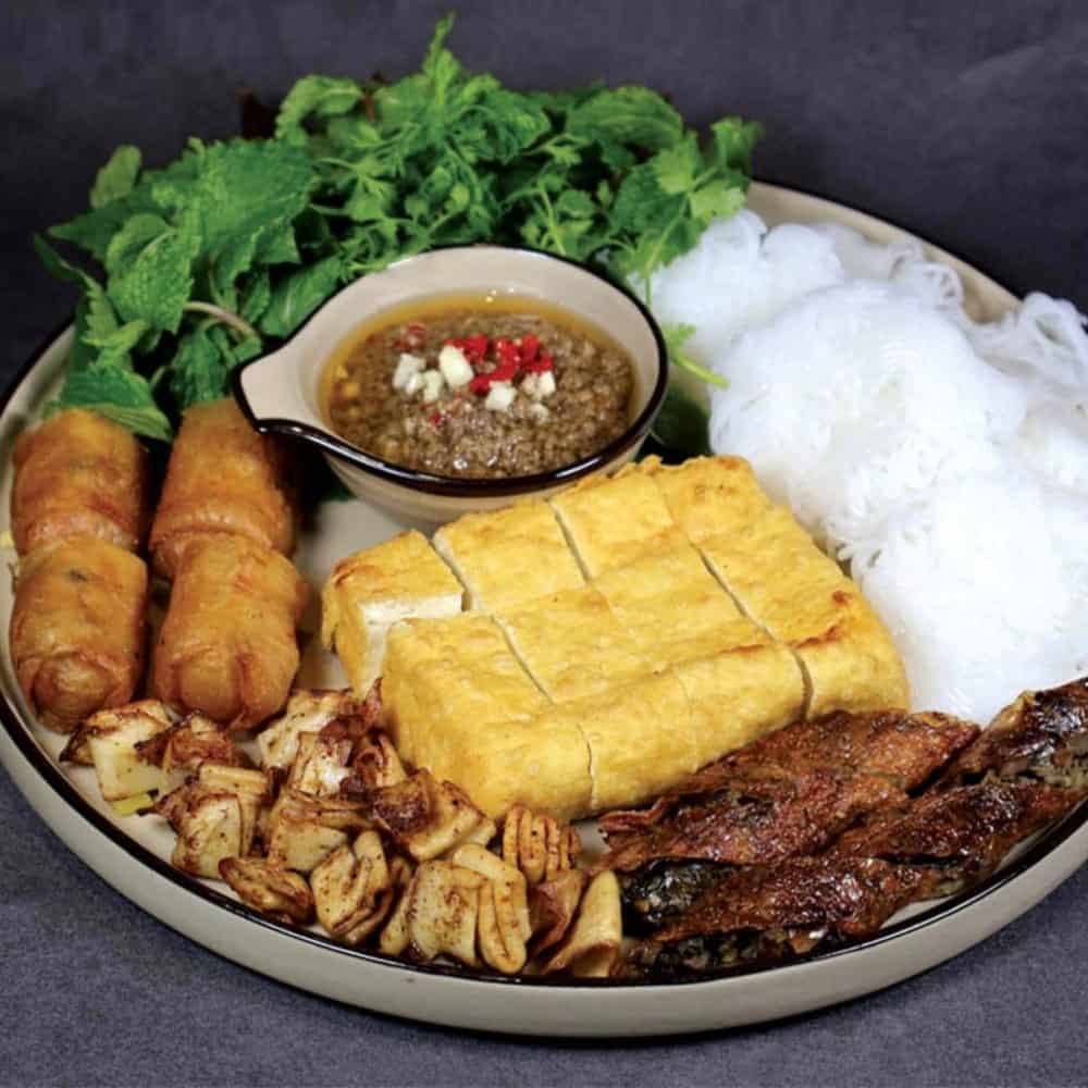 a full plate of golden tofu with rice, mock meat, and green leafy lettuce at Chayfood in hanoi