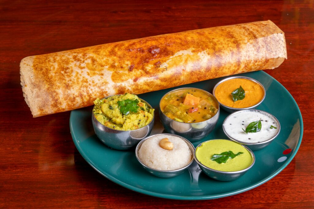 Crispy vegan South Indian dosa served with coconut chutney, sambar, and vegetable sides