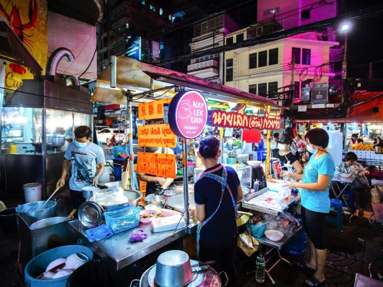 street food vendors with neon lights illuminated at night time in thailand