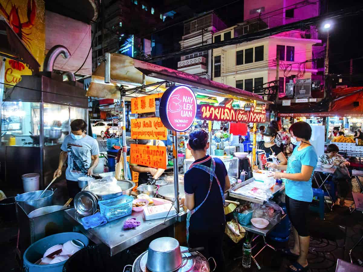 street food vendors with neon lights illuminated at night time in thailand