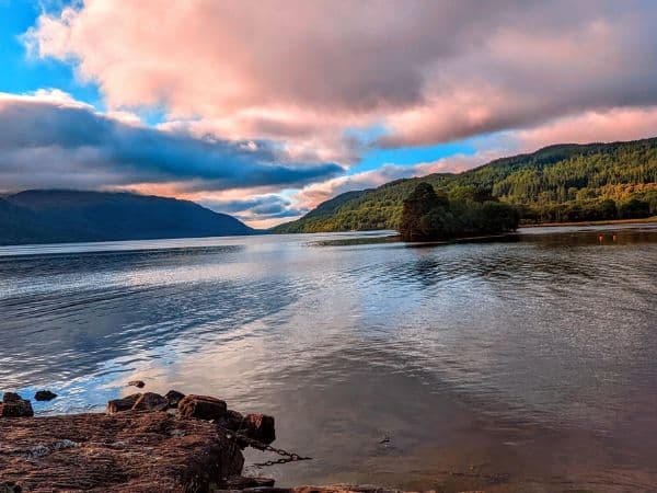 pink and white clouds over loch ness as the sun is setting