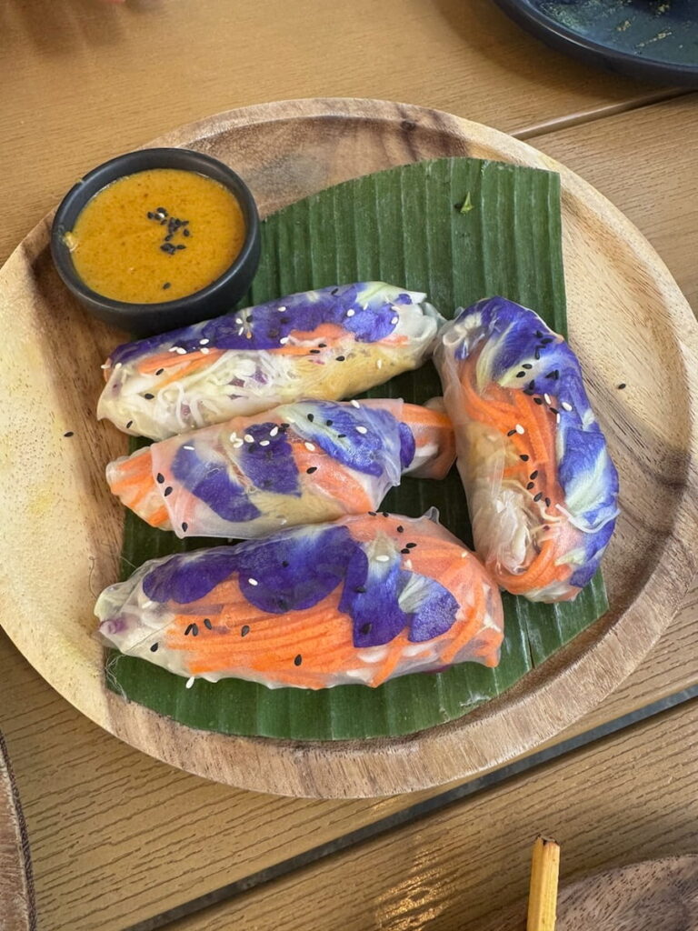 colorful vegan rainbow rolls with bright purple flowers in thailand