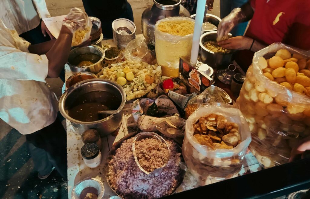 Busy Indian street food stall preparing fresh snacks with puffed rice, potatoes, chutneys, and crispy toppings, showcasing the vibrant street food scene in India.
