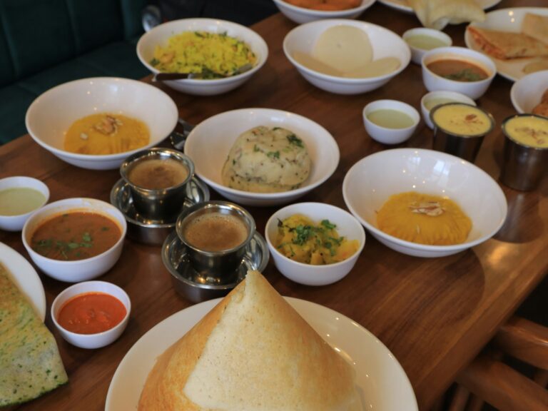 Traditional South Indian vegan breakfast featuring dosa, idli, vada, sambar, chutneys, and Indian coffee.