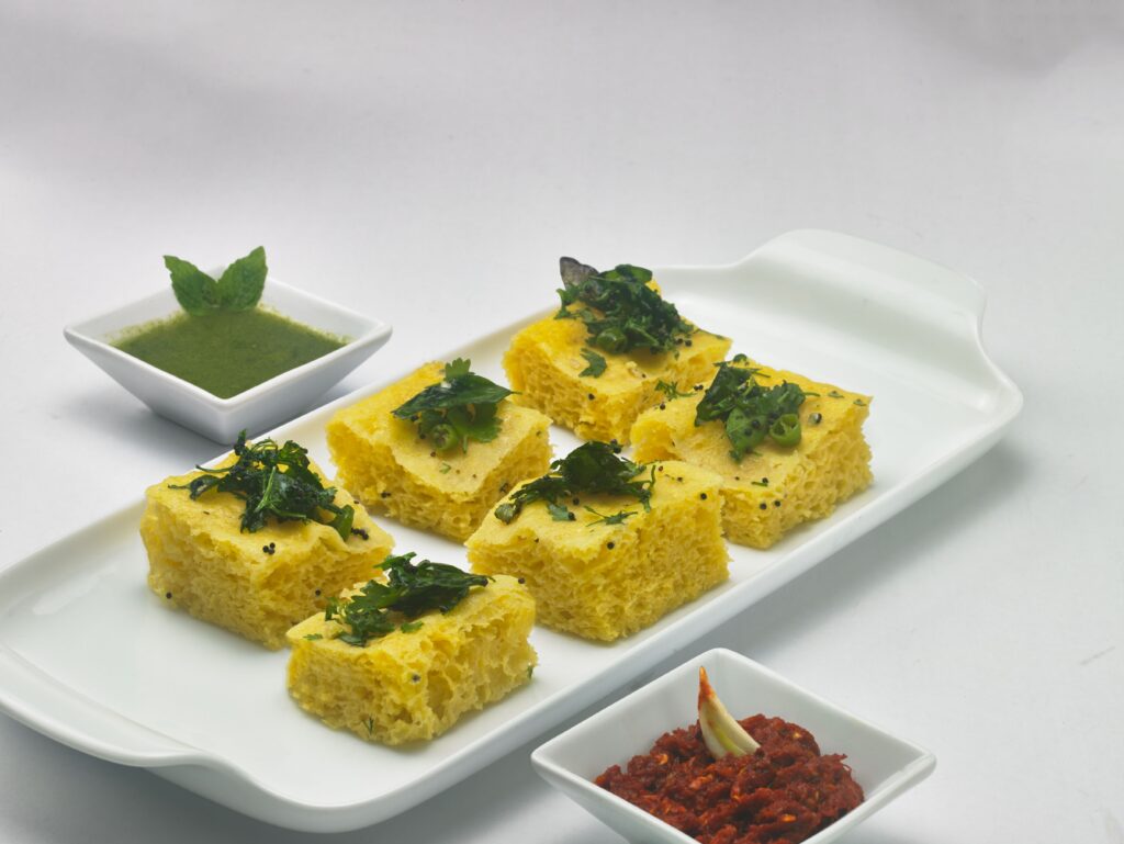 Traditional Gujarati dhokla with green chutney, a naturally vegan Indian chickpea flour snack.