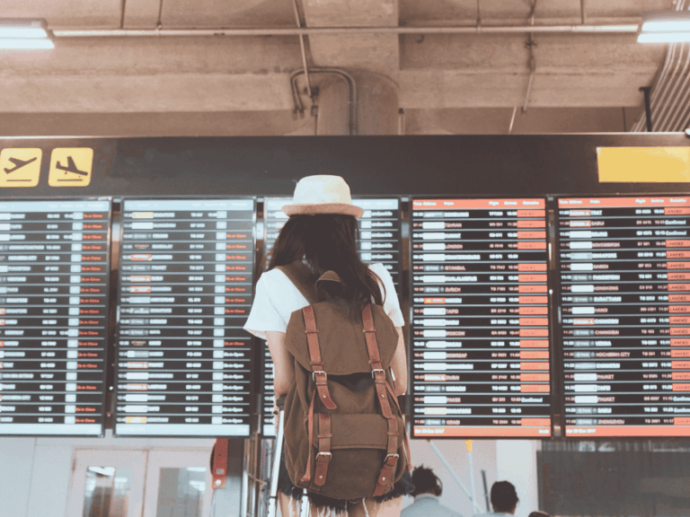 Traveler with a backpack checking the airport departure board before a flight.