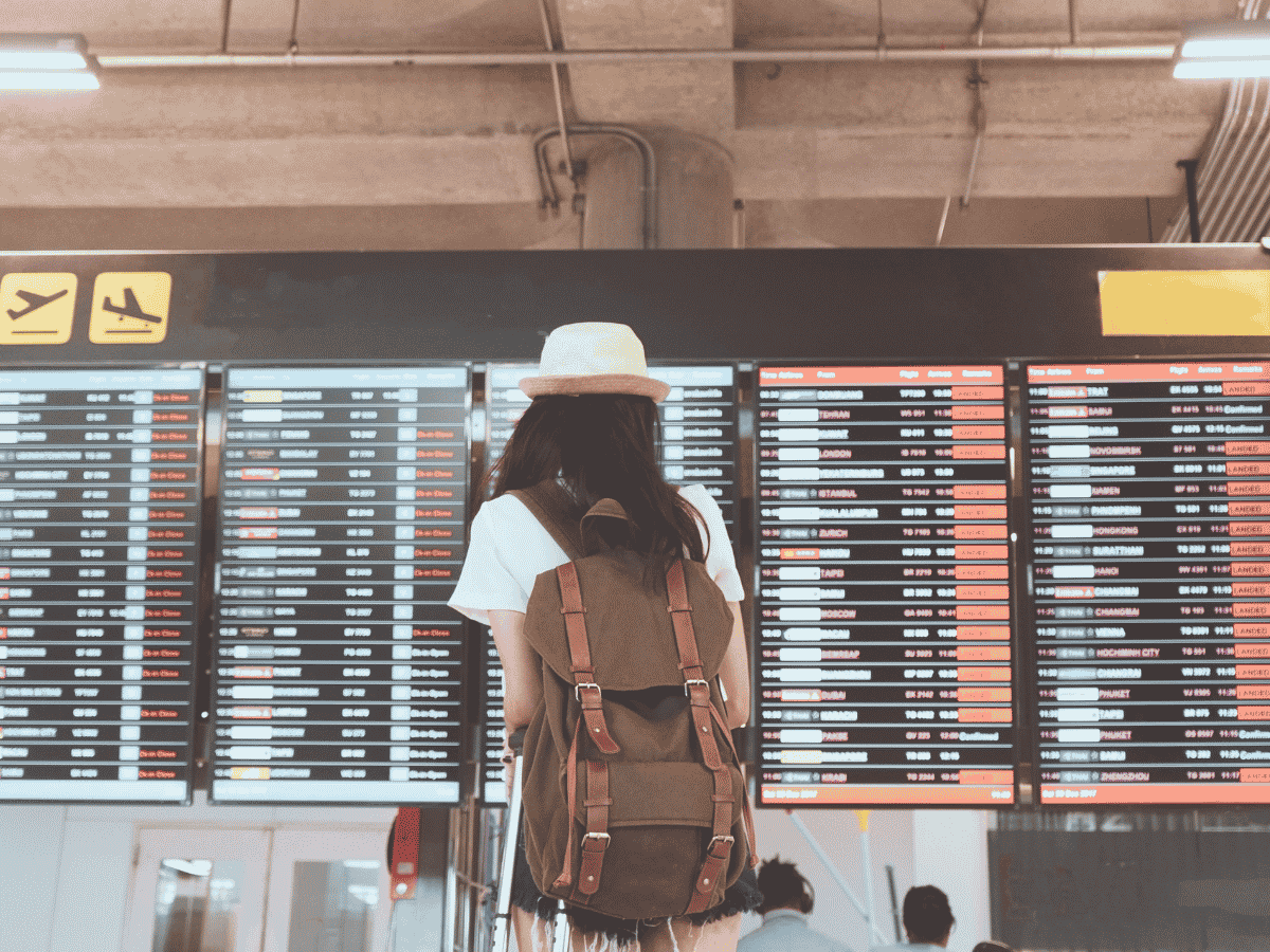 Traveler with a backpack checking the airport departure board before a flight.