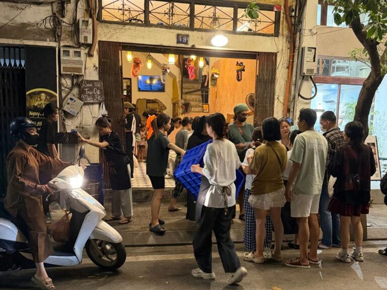 Crowds gathering outside a busy restaurant on a lively street in Hanoi, Vietnam, at night