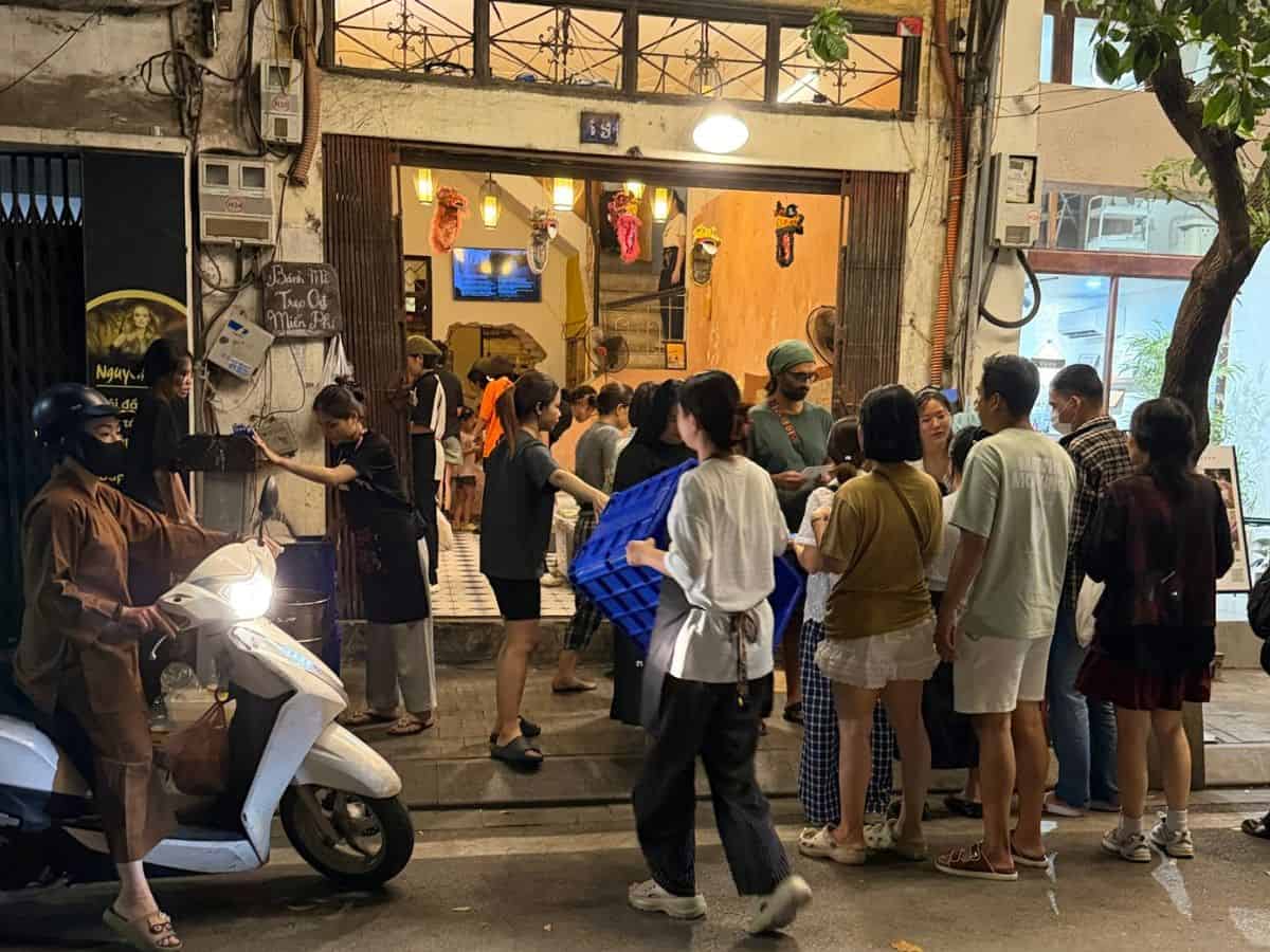 Crowds gathering outside a busy restaurant on a lively street in Hanoi, Vietnam, at night