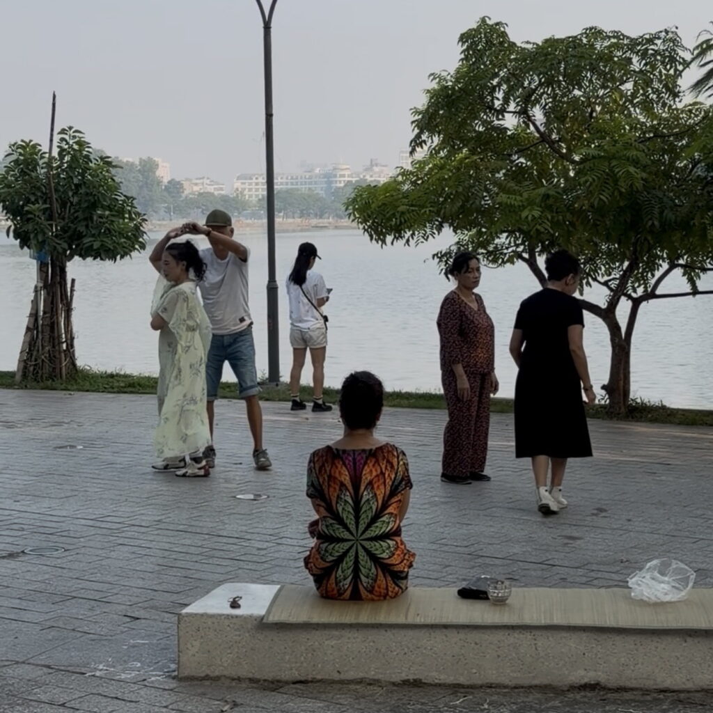 Locals dancing together outdoors near a lake in Hanoi, Vietnam.