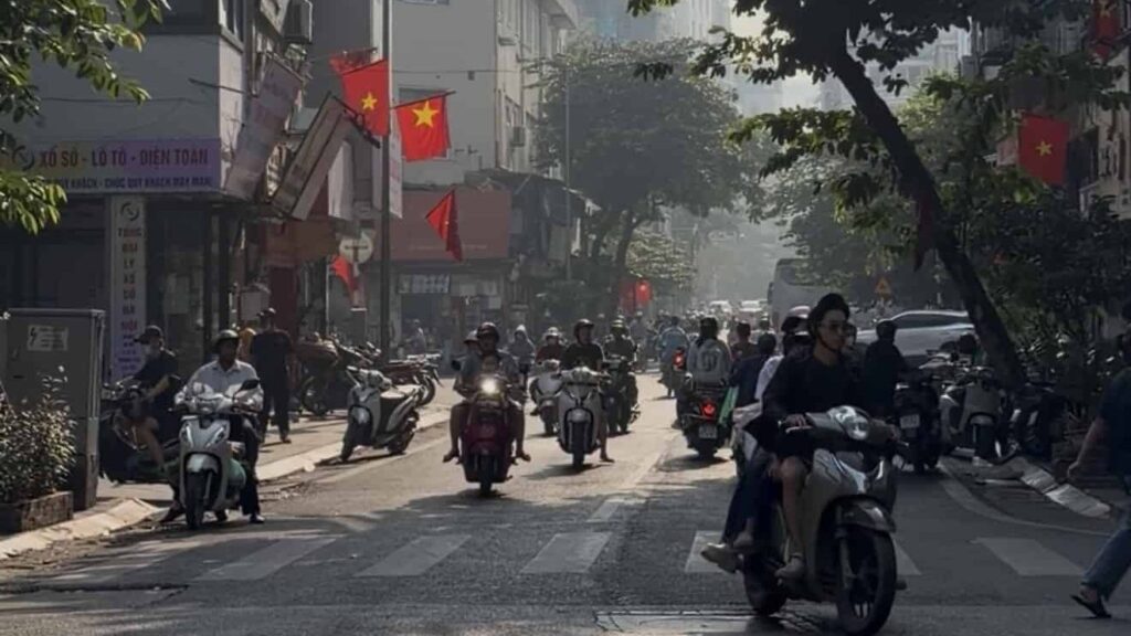 Busy street in Hanoi, Vietnam, with motorbikes and red Vietnamese flags hanging overhead