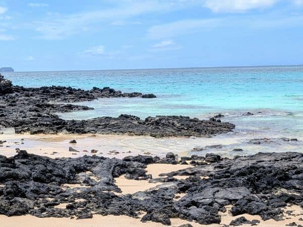 an isolated white sand beach with volcanic rocks in the galapagos islands