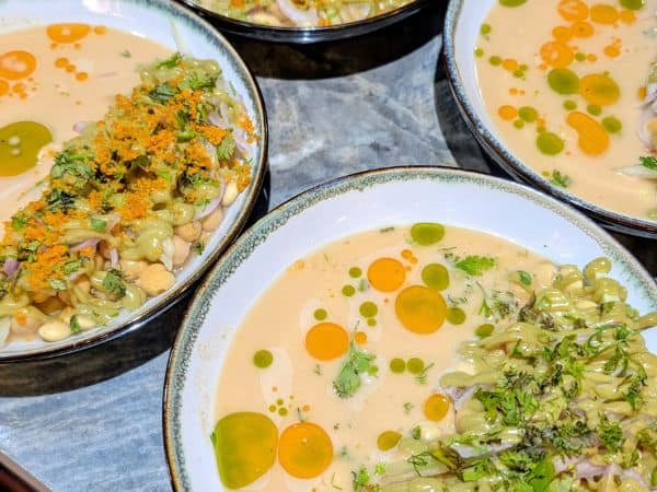 four large round bowls of bright yellow vegan ceviche with pops of orange and green